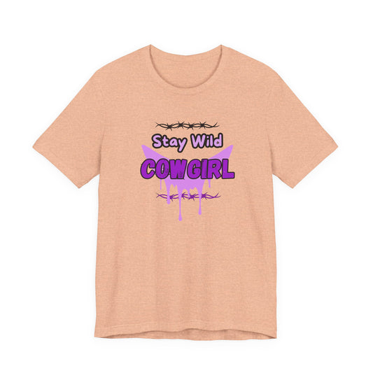 Cowgirl Western Tee with playful 'Stay Wild COWGIRL' graphic in purple on a light peach background.